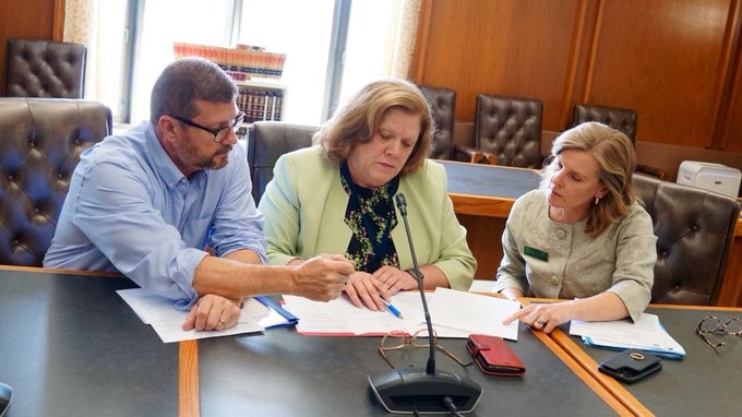 Sharon Carson reviewing legislation with colleagues at a committee table