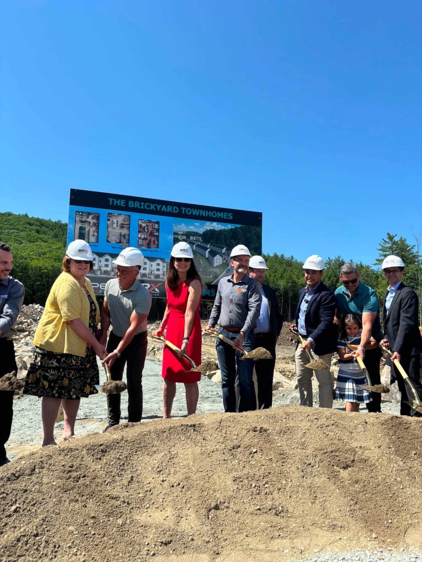 Sharon Carson holding a gold shovel with local leaders at the Brickyard Townhomes groundbreaking